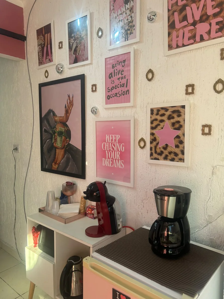 Cantinho do café do studio com parede de quadros decorativos em tons de rosa